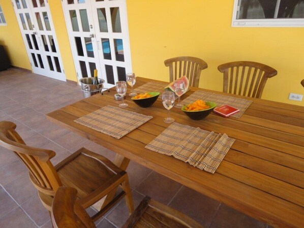 A wooden dining table with placemats, chairs, and a fruit bowl.
