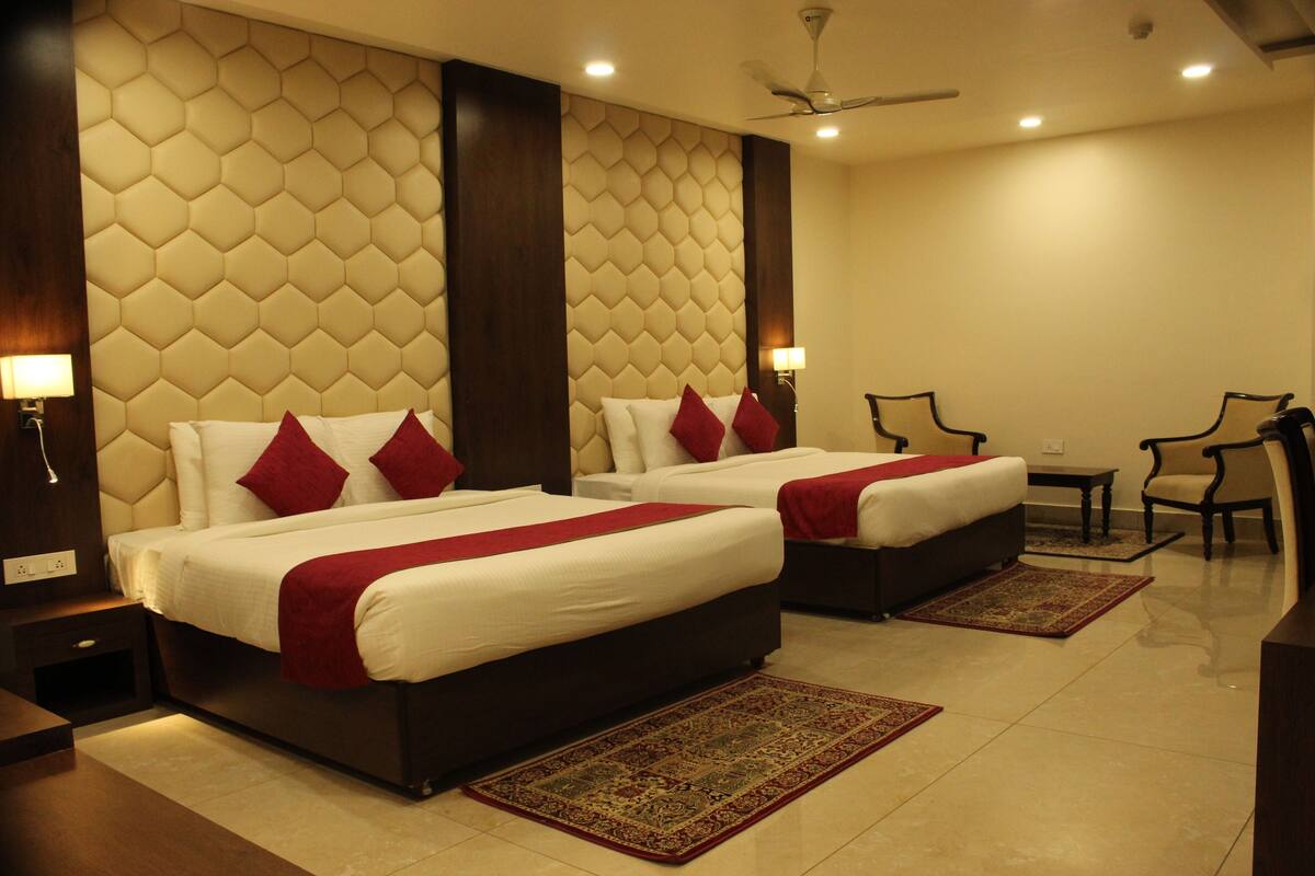 A hotel room with two beds, a desk, and a chair.