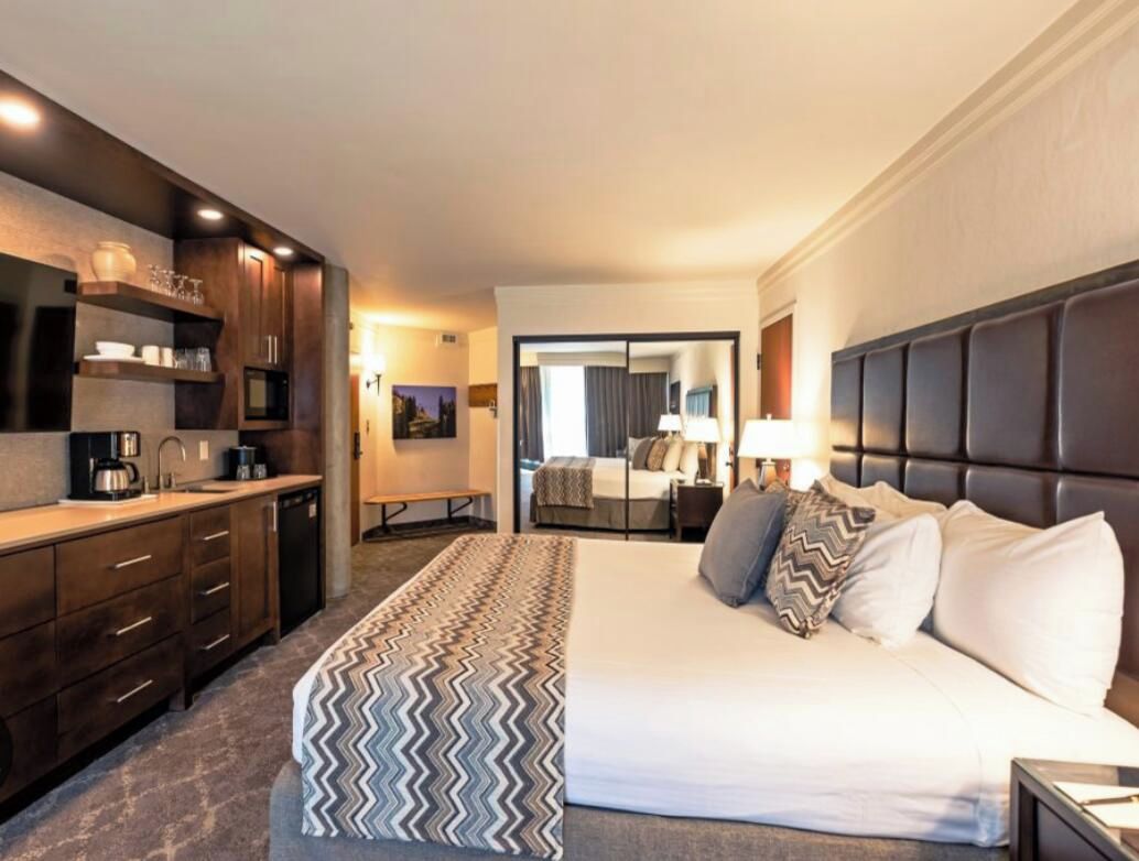 Ein Hotelzimmer mit Bett, Schreibtisch, Küchenzeile und Bad.