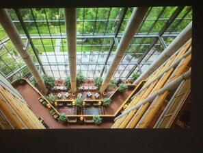 A high-ceilinged atrium with a central seating area surrounded by trees and a glass ceiling. - Snowbird Cliff Club Sat. Dec 19, 2026 till Sat. Dec. 26, 2026 Pinnacle Platinum (Snowbird)