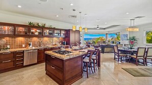 Una cocina amplia con una isla grande, armarios de madera oscura y vista al área de comedor.