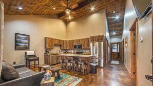 A spacious living area with a leather sofa, a coffee table, and a bar area with stools.