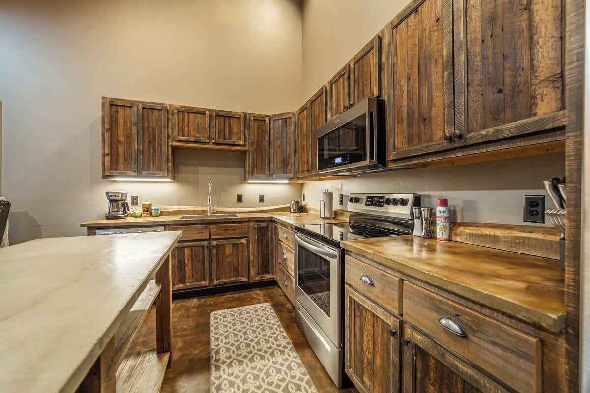 A kitchen with wooden cabinets, stainless steel appliances, and a marble countertop.