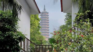 A staircase leading to a building with a pagoda-style tower in the background, surrounded by lush greenery and a metal railing.
