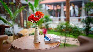 Una mesa redonda de madera con un jarrón de flores rojas y un libro.