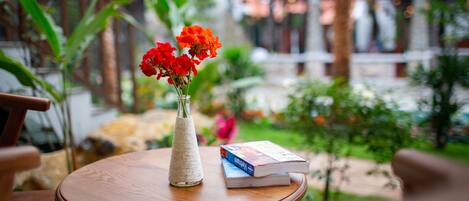 Una mesa redonda de madera con un jarrón de flores rojas y un libro.