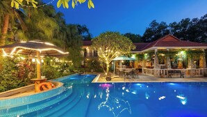 A swimming pool with a thatched-roof gazebo, outdoor seating, and a covered area with plants. - Bai Dinh Garden Resort & Spa Ninh Binh (Tay Hoa Lu)