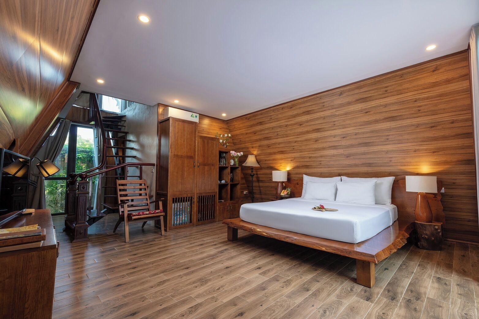 Un dormitorio con cama, paredes de madera, una escalera y vistas al verdor.