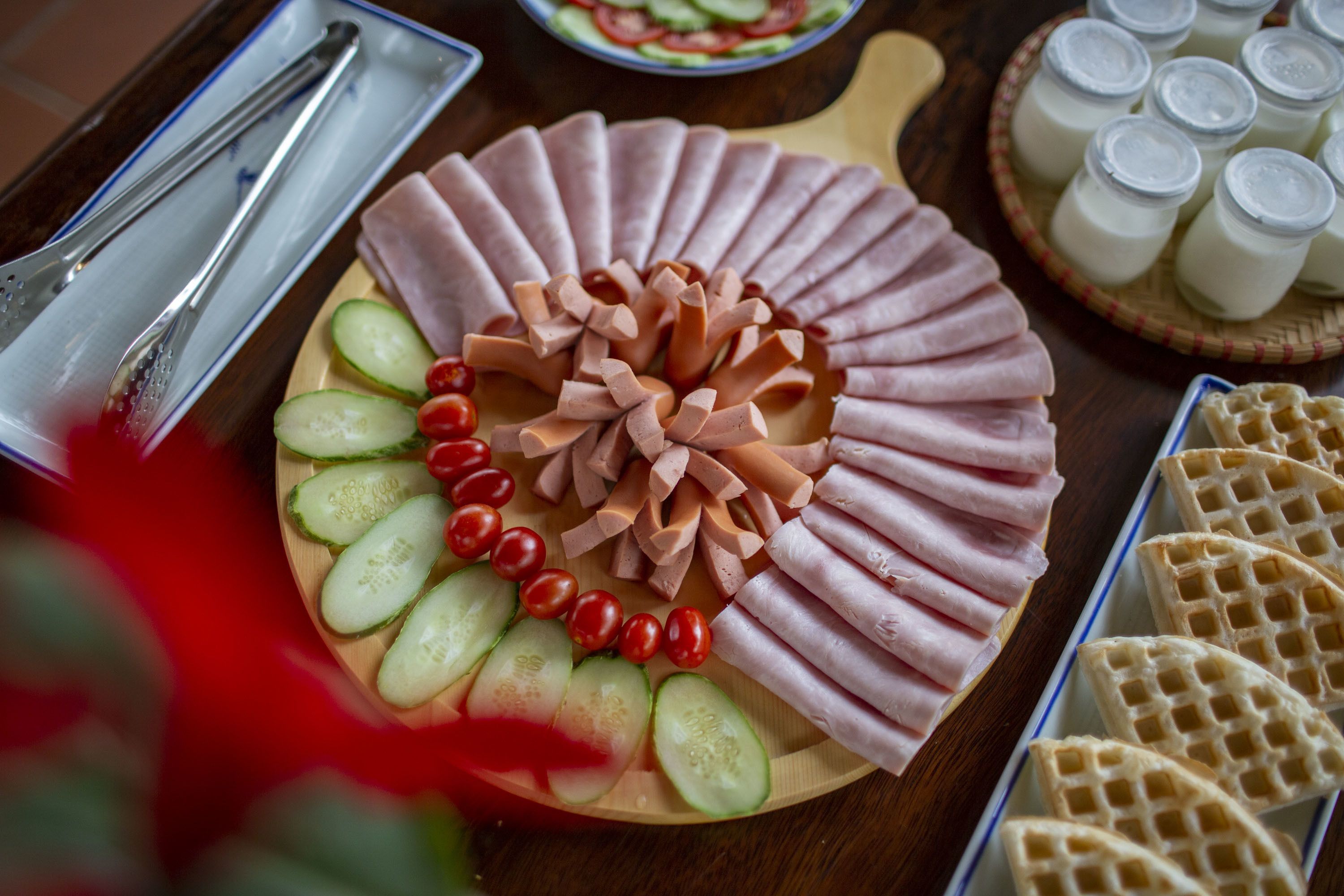 A charcuterie board with sliced meats, cheese, and vegetables.