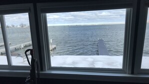 A view from a window overlooking a body of water with a dock and a buoy.