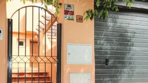 Ein verschlossener Eingang mit einem Metalltor, einer Treppe, die zu einer Tür führt, und zwei Informationstafeln an der Wand.