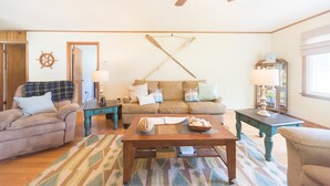 Un salon chaleureux avec un canapé, des fauteuils, une table basse et un plancher en bois.