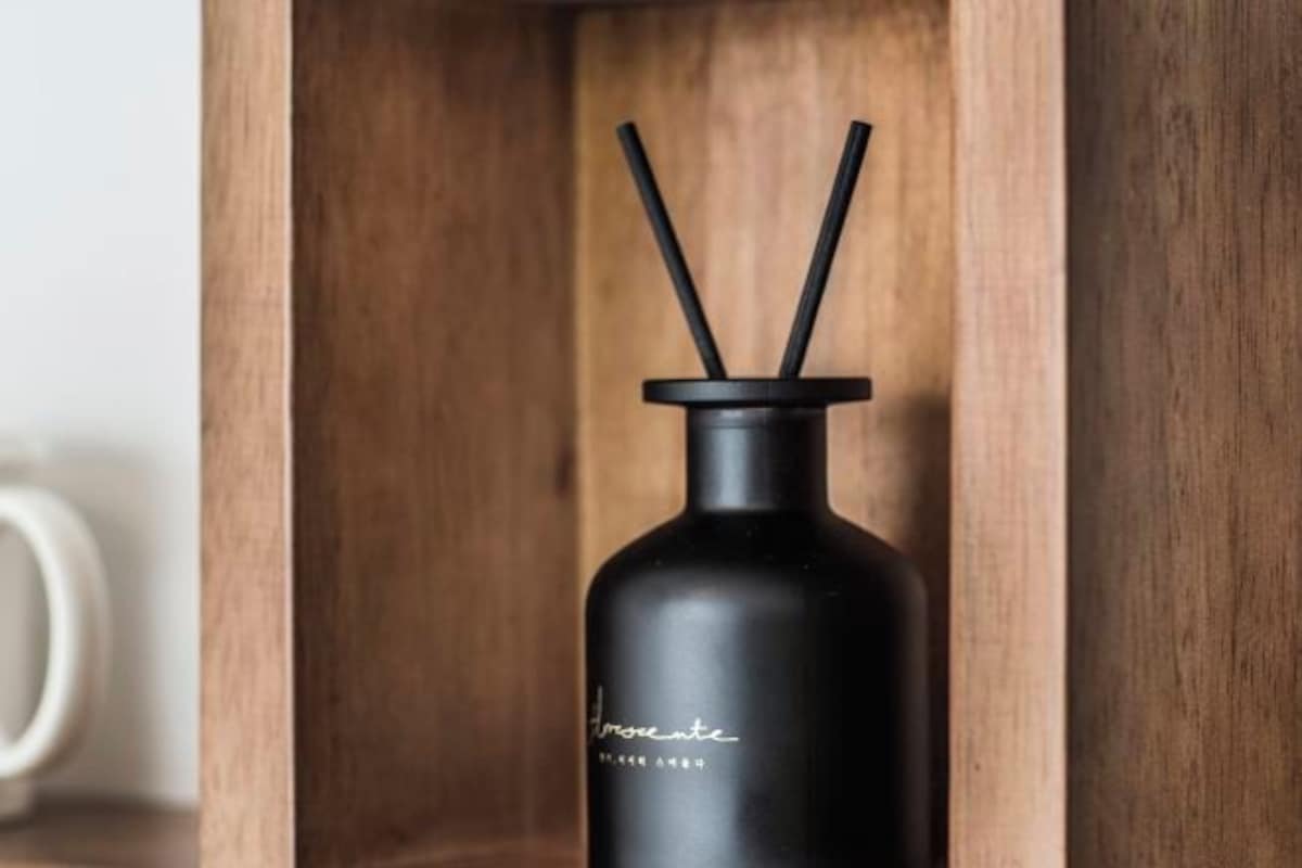 Una botella negra con etiqueta y dos pajitas negras, dentro de una caja de madera.
