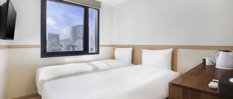 A hotel room with a bed, a wooden nightstand, a coffee maker, and a television mounted on the wall.