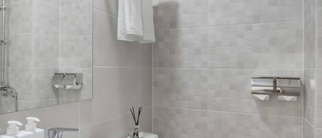Ein modernes Badezimmer mit Waschbecken, Toilette und Duschbereich in Weiß.