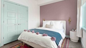 A bedroom with a bed, a wardrobe, a nightstand, and a window with curtains.