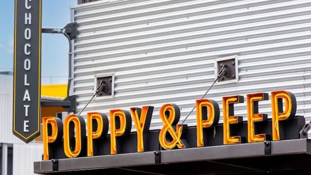 A storefront with a sign reading "Poppy & Peep" and a smaller sign above it stating "Chocolate."