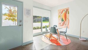 A modern interior with a dining area, large windows, and a view of the outdoors.