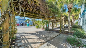 Un espace extérieur abrité, doté d’un chemin de gravier, d’une pergola en bois et de plantes tropicales.