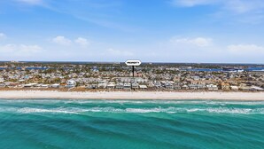 Ein Küsteneigentum mit Blick auf den Strand, ein Schild mit der Aufschrift 'PROPERTY' und ein dicht bebautes Wohngebiet im Hintergrund.