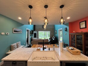 A kitchen with a marble countertop, a built-in sink, and pendant lighting.