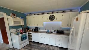 Eine Küche mit weißen Schränken, einer Mikrowelle, einem Herd und einem Kühlschrank.