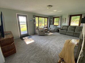Een woonkamer met een bank, fauteuils en een houten kast.