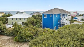A coastal residential area with houses, including a prominent blue house with a balcony and a white house with a green roof. - Large, Pet Friendly, Private Pool, Golf Cart,Easy Beach Access (Emerald Isle)