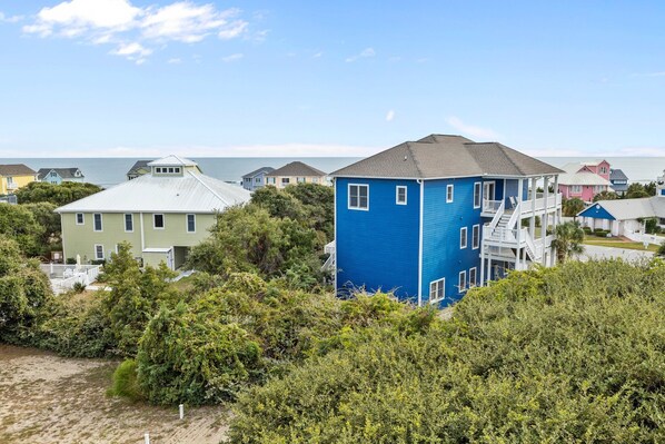 A coastal residential area with houses, including a prominent blue house with a balcony and a white house with a green roof. - Large, Pet Friendly, Private Pool, Golf Cart,Easy Beach Access (Emerald Isle)
