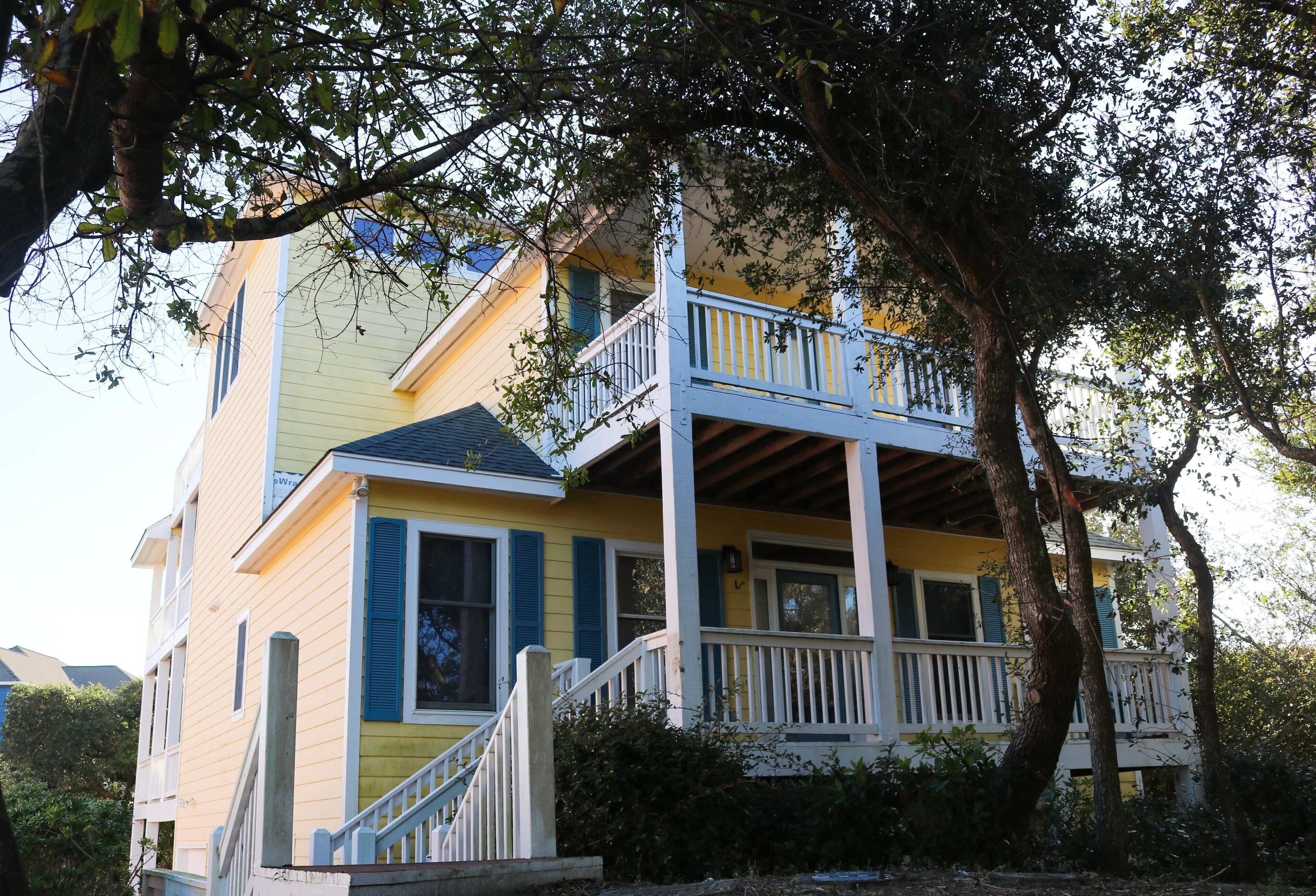 A two-story house with a balcony, a porch, and a staircase leading to the entrance.