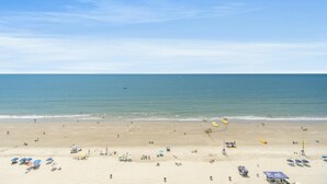 Ein Strand mit Sonnenschirmen, Liegestühlen und einem Rettungsturm.