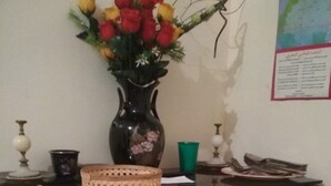 Een kleintje tafeltje met een bloevas, een kaars, een kopje en een paar boeken.