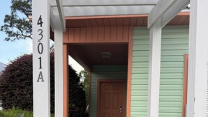 A house with a porch, a door, and a number sign.