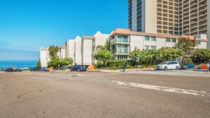 A coastal hotel with a parking lot, a view of the ocean, and a tall building in the background. - Heart of La Jolla Gem - Newly Renovated! (La Jolla)