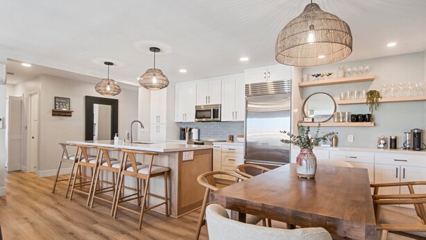 A modern kitchen with white cabinets, stainless steel appliances, and a wooden dining table. - Heart of La Jolla Gem - Newly Renovated! (La Jolla)