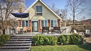 A two-story house with a front porch, a covered patio, and a small garden area. - Charming Beachfront Home, large backyard and deck, walk over dune to stop2 beach (Michigan City)