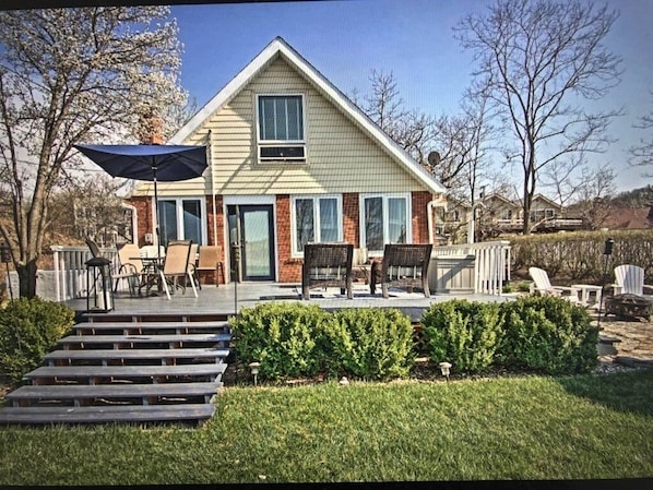 A two-story house with a front porch, a covered patio, and a small garden area.