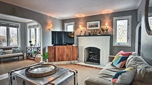 A living room with a fireplace, a sofa, a coffee table, and a television. - Charming Beachfront Home, large backyard and deck, walk over dune to stop2 beach (Michigan City)