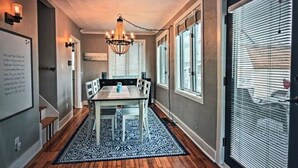 A dining area with a wooden table and chairs, a chandelier, and a patterned rug. - Charming Beachfront Home, large backyard and deck, walk over dune to stop2 beach (Michigan City)
