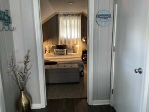 Um quarto com uma cama, mesa de cabeceira, abajur e relógio de parede.