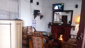 A living room with a television, a fireplace, and patterned furniture. - Maggies Cottage NuwaraEliya (Nuwara Eliya)