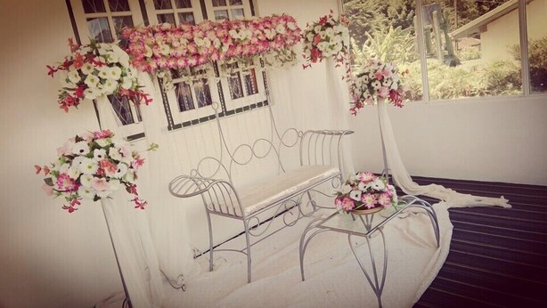 A covered outdoor seating area with metal chairs and tables, decorated with hanging floral arrangements. - Maggies Cottage NuwaraEliya (Nuwara Eliya)