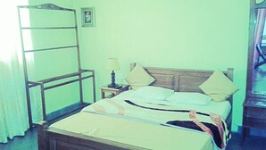 A single bed with a wooden headboard, a nightstand with a lamp, and a mirror on the wall. - Maggies Cottage NuwaraEliya (Nuwara Eliya)