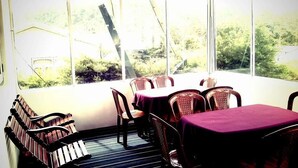A room with a table and chairs, large windows, and a view of greenery outside. - Maggies Cottage NuwaraEliya (Nuwara Eliya)