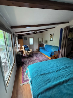 Une chambre à coucher avec un lit, une chaise, un canapé, une commode et une fenêtre.