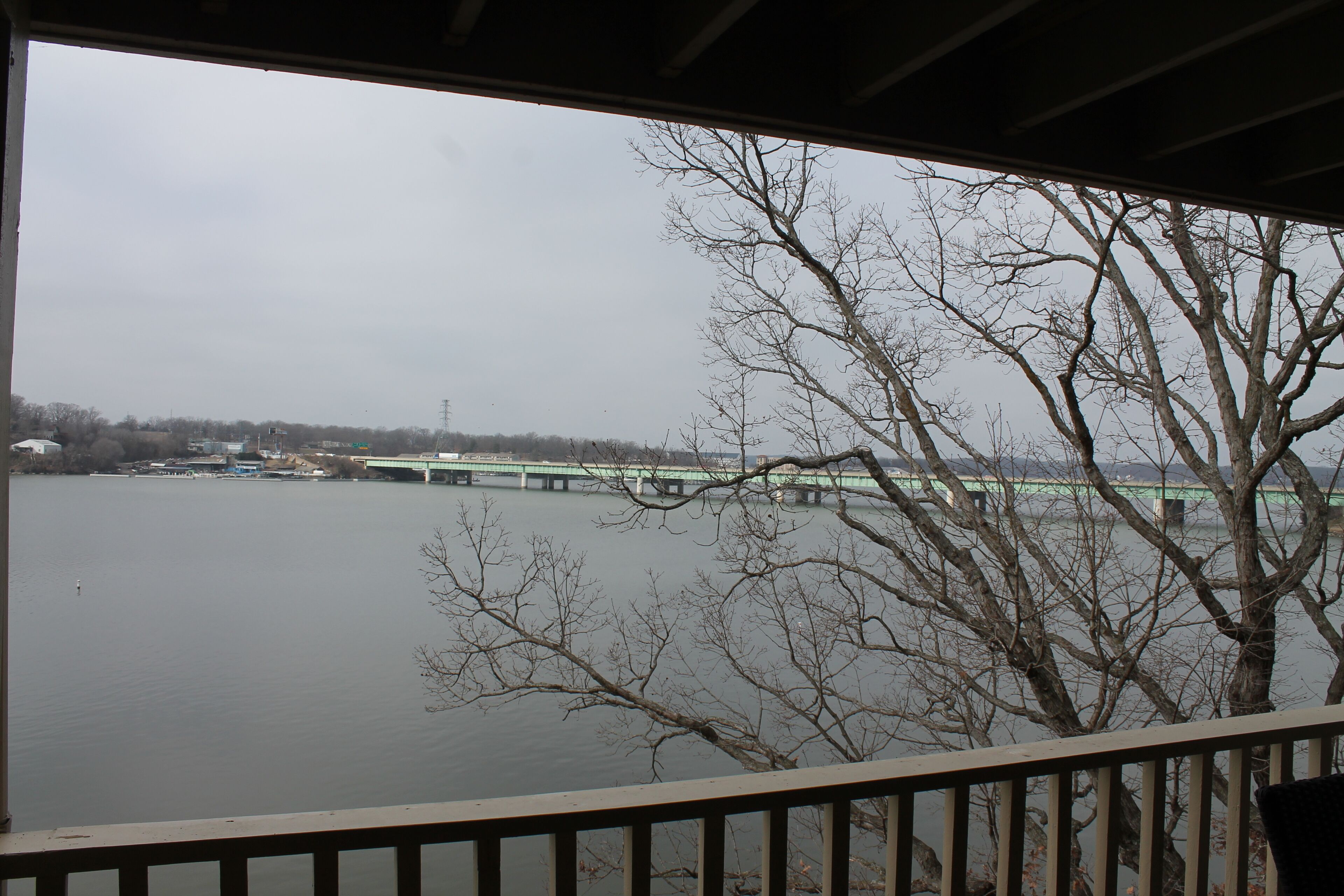 A view from a covered area overlooking a river with a bridge in the distance.