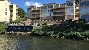 A waterfront hotel with multiple balconies, a sign reading "Parkside Place," and a view of the water. - Freshly Remodeled Condo with amazing Grand Glaze View! (Osage Beach)