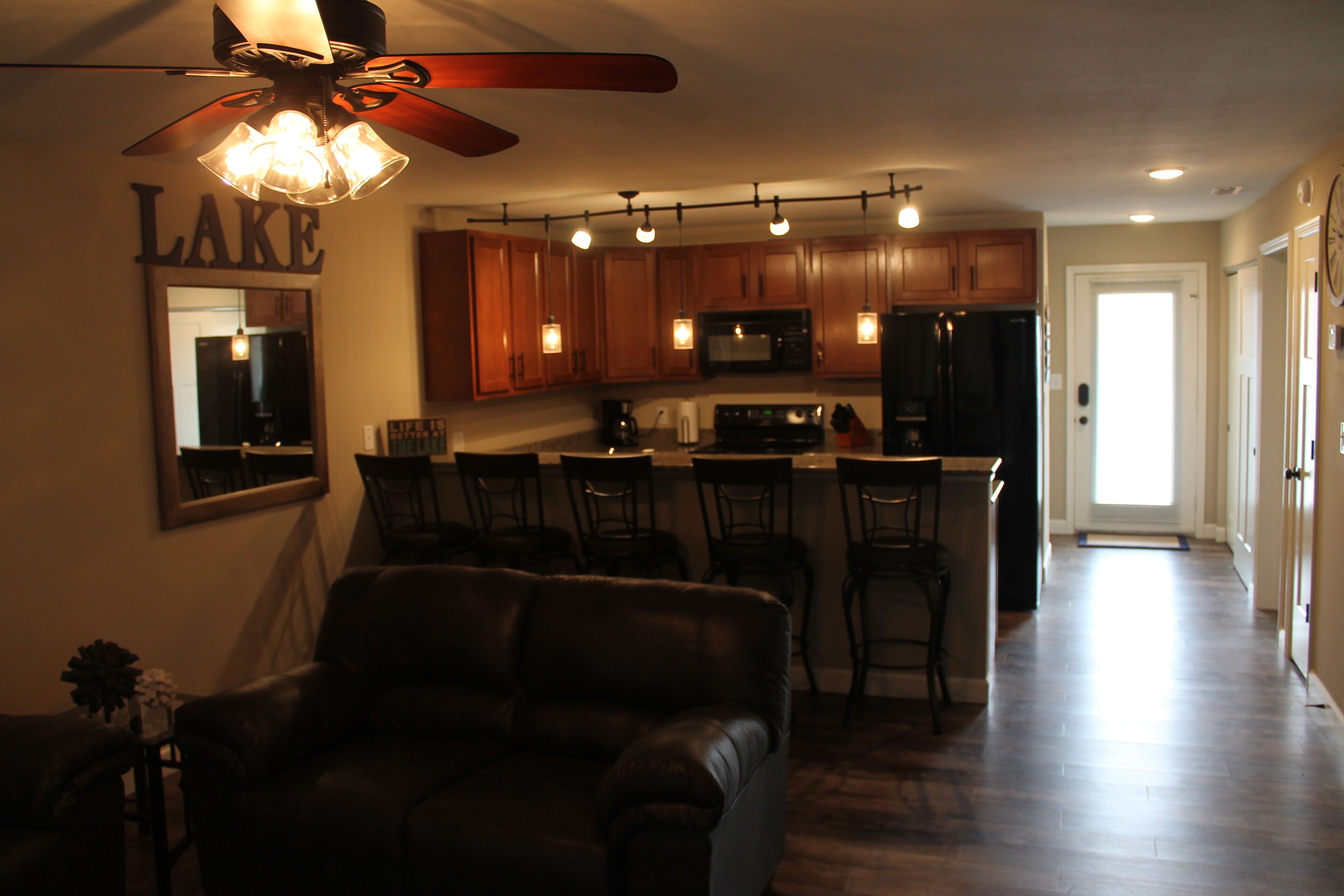 A modern kitchen with wooden cabinets, a bar area, and a ceiling fan.