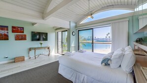 Une chambre spacieuse avec un grand lit, une télévision et une vue sur la plage.