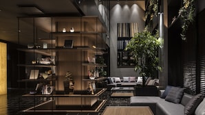 A modern interior with a central seating area, a bookshelf, and a staircase leading to an upper level. - Bespoke Hotel Shinsaibashi (Osaka)